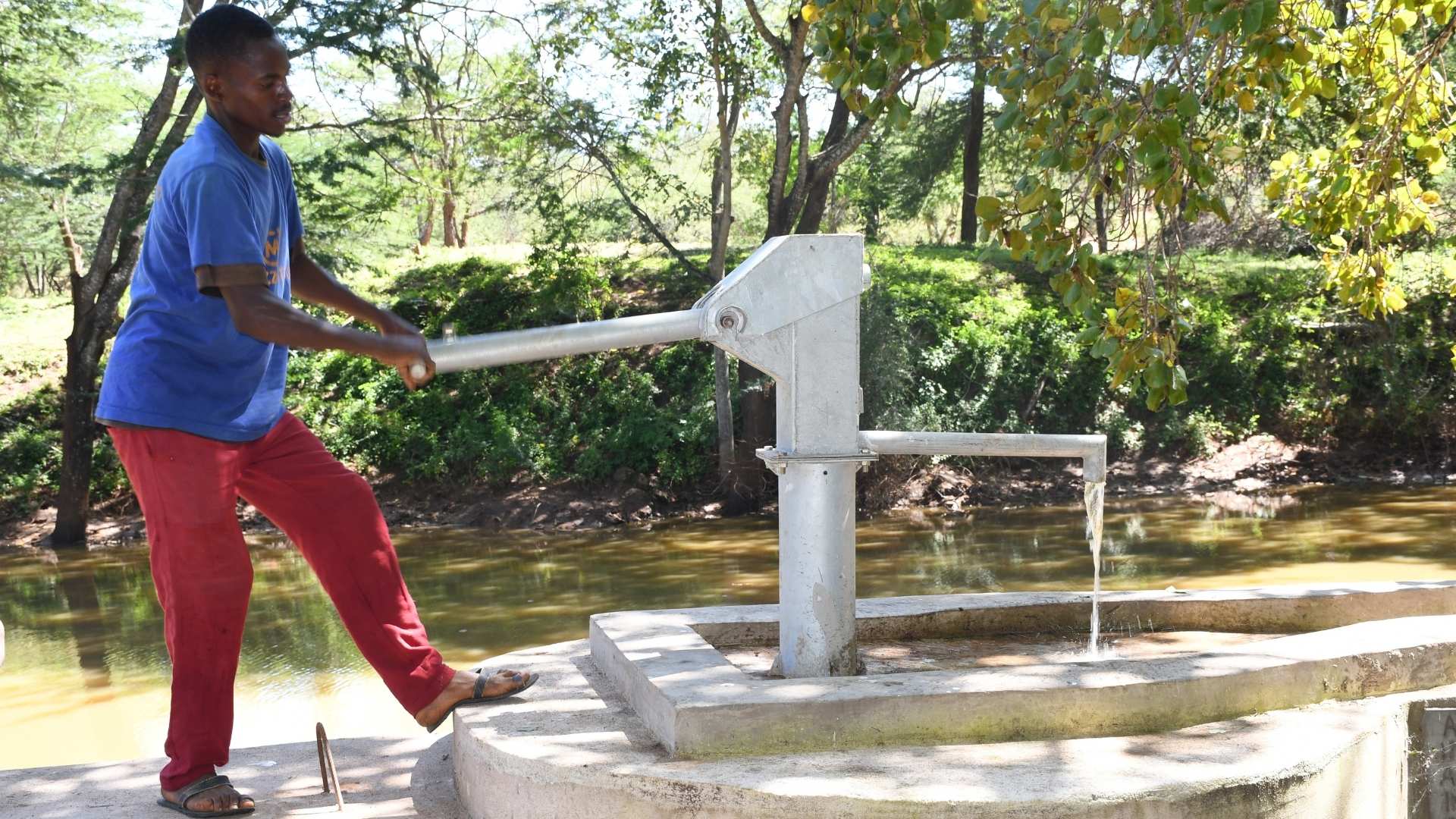 man operates safe water pump