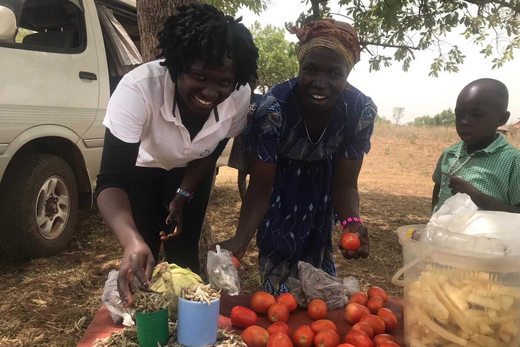 two women smile with their tomato produce ready for sale
