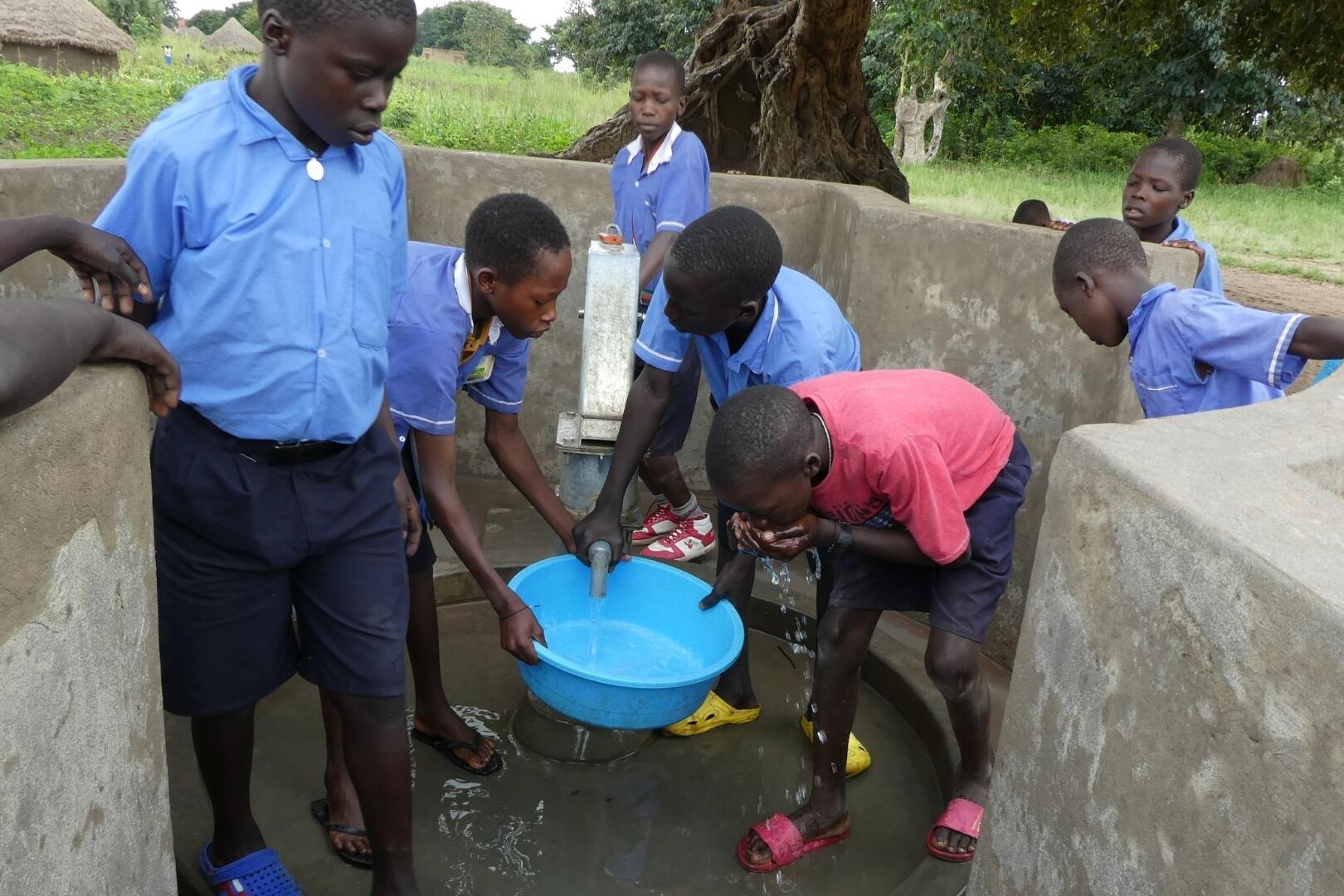 school boys fill up water from pump